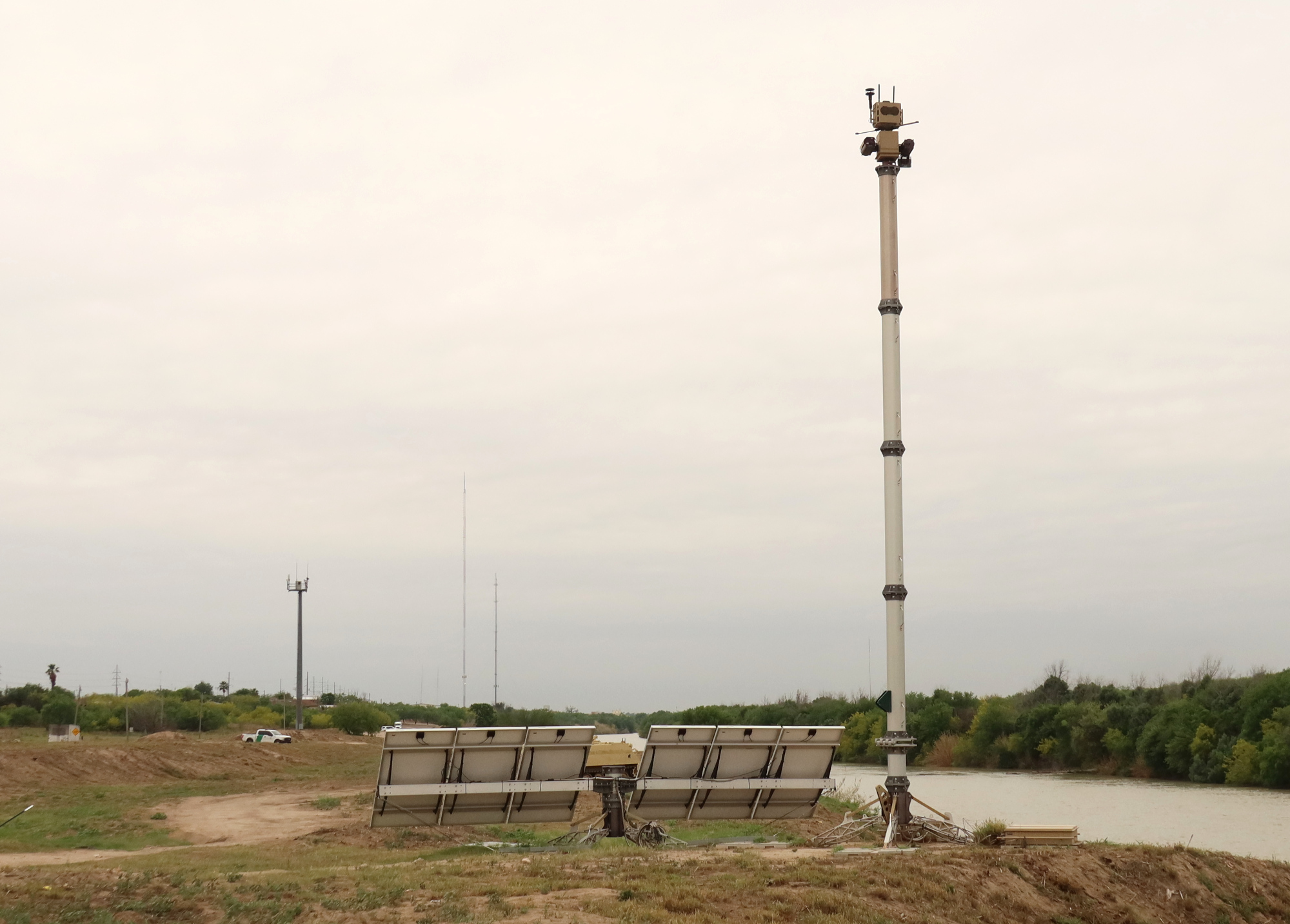 An Autonomous Surveillance Tower and an RVSS tower along the Rio Grande. Two surveillance towers and a Border Patrol vehicle along the Rio Grande
